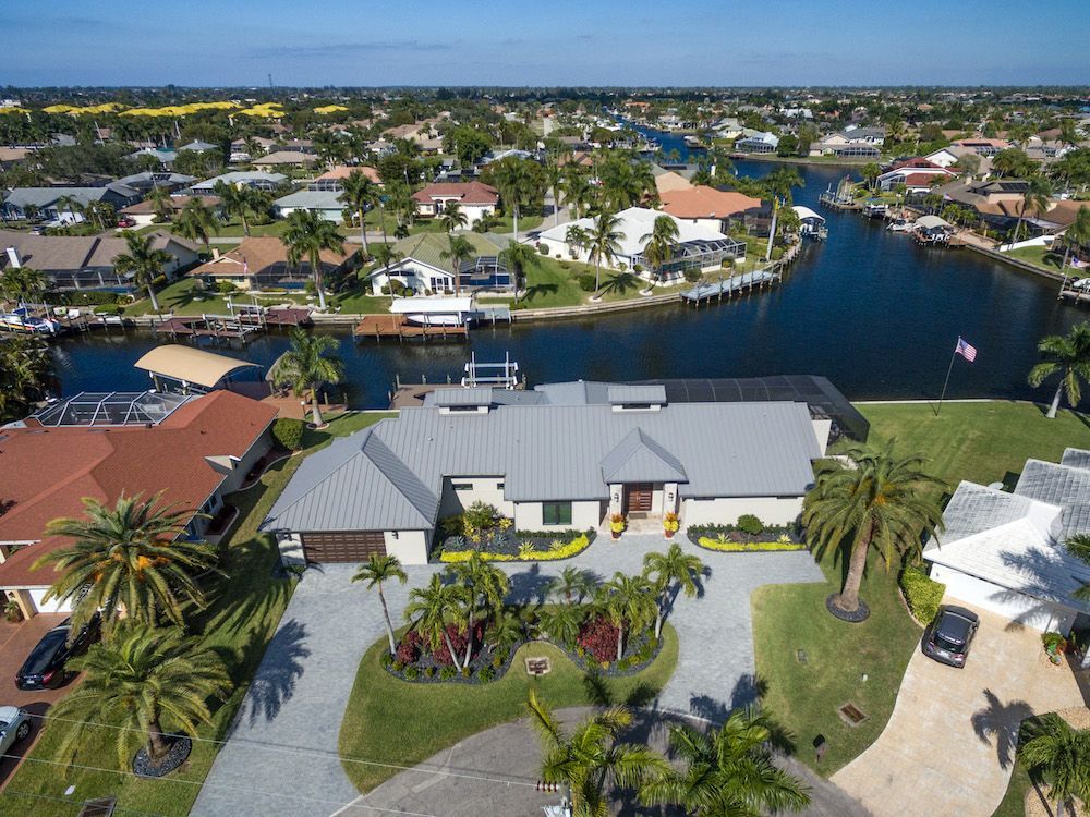 An aerial view of a house in a residential area next to a body of water.