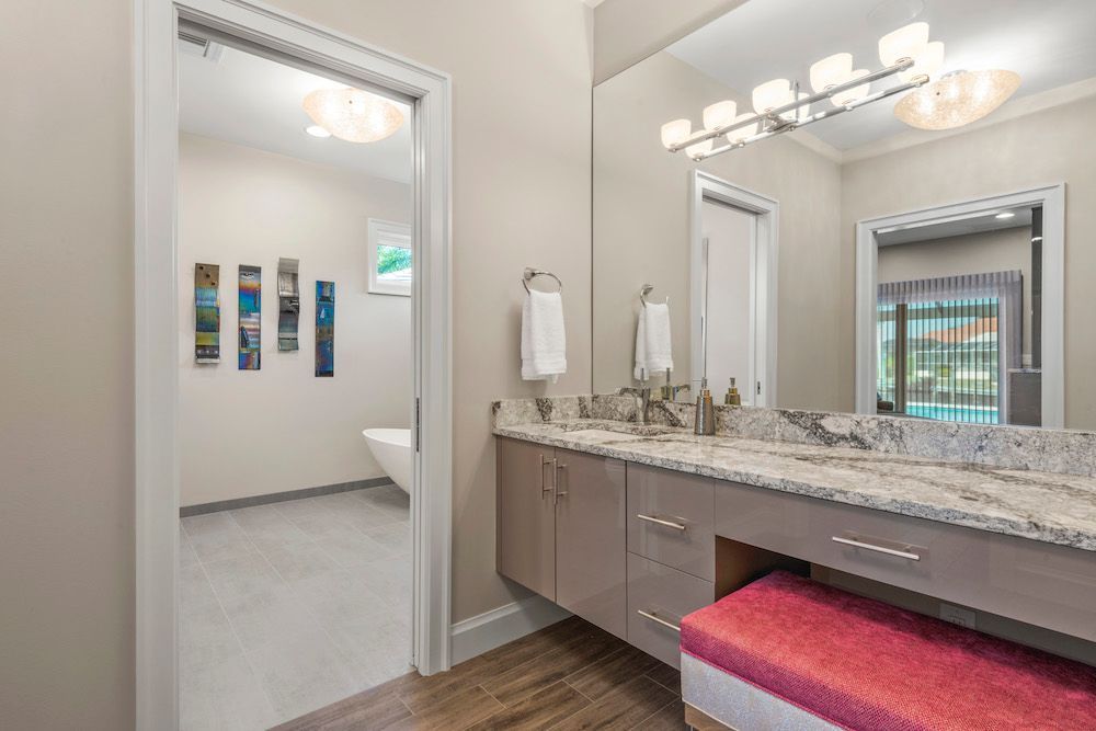A bathroom with two sinks , a large mirror and a pink bench.