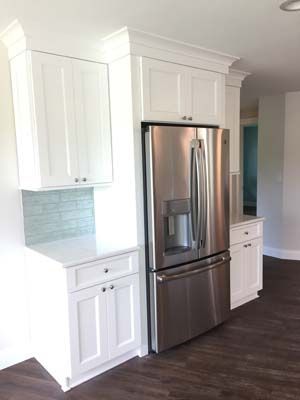 A kitchen with white cabinets and a stainless steel refrigerator
