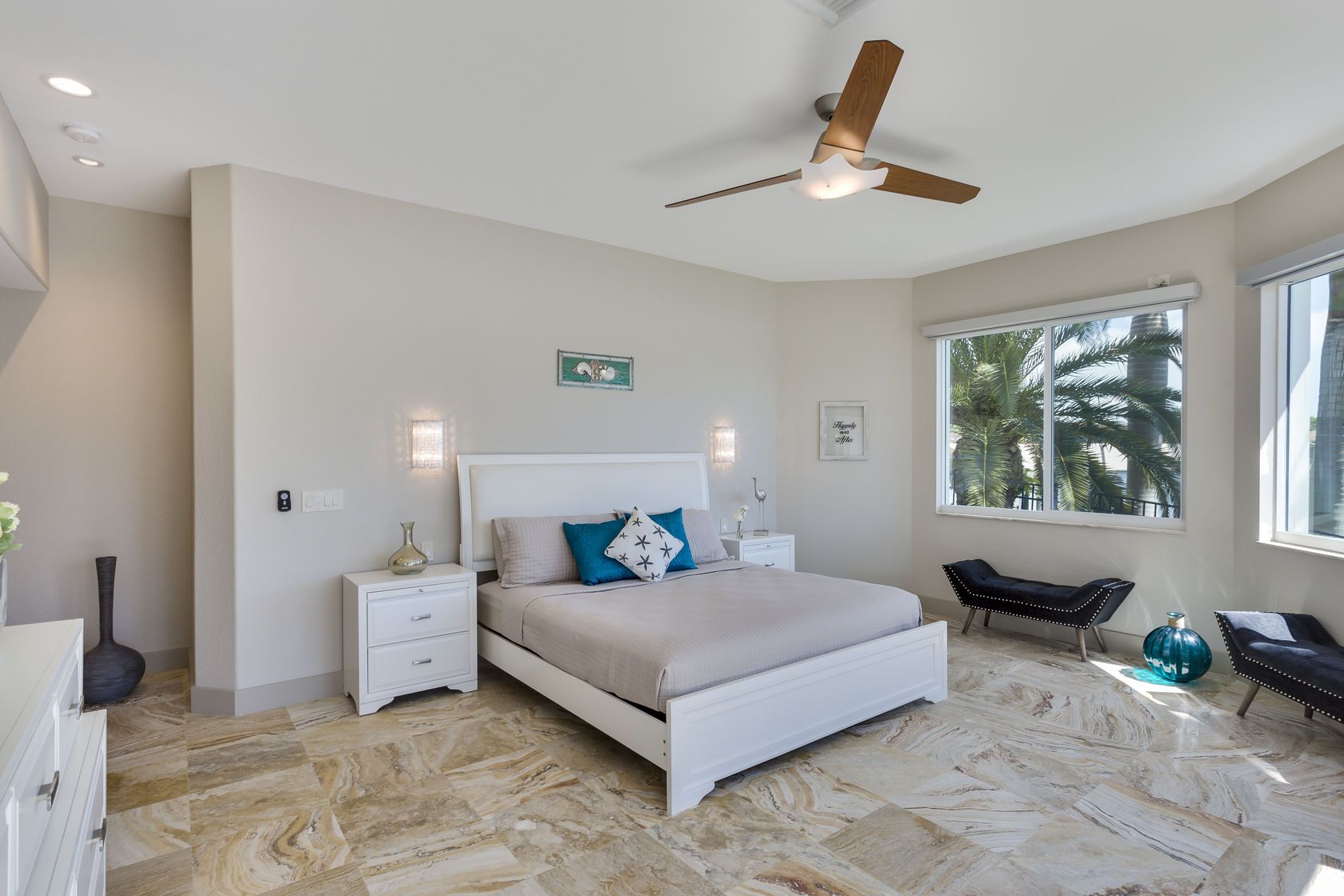 A bedroom with a king size bed , nightstands , and a ceiling fan.