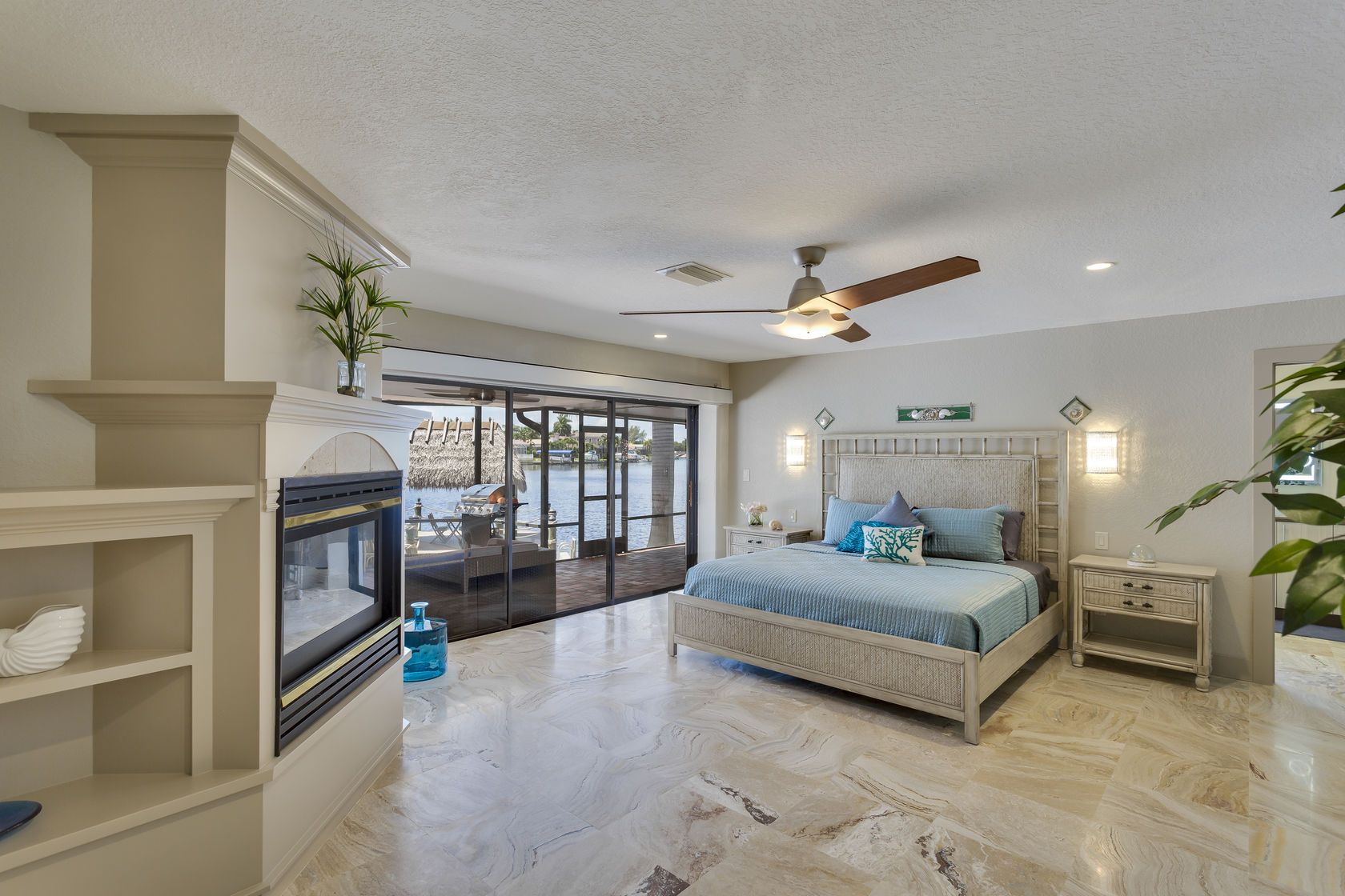 A bedroom with a king size bed , fireplace and sliding glass doors.