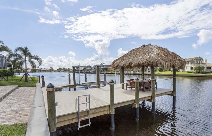 A dock with a thatched hut on top of it in the middle of a body of water.