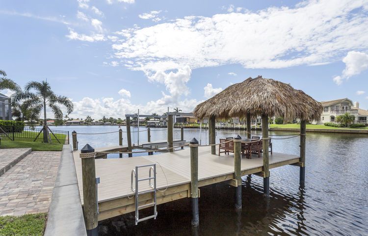 A dock with a thatched hut on top of it overlooking a body of water.