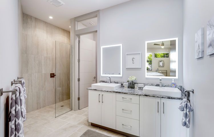 A bathroom with two sinks , two mirrors and a walk in shower.
