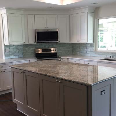 A kitchen with white cabinets , granite counter tops , a stove and a microwave.