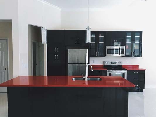 A kitchen with black cabinets and a red counter top
