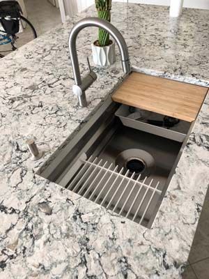 A kitchen sink with a wooden cutting board on top of it.