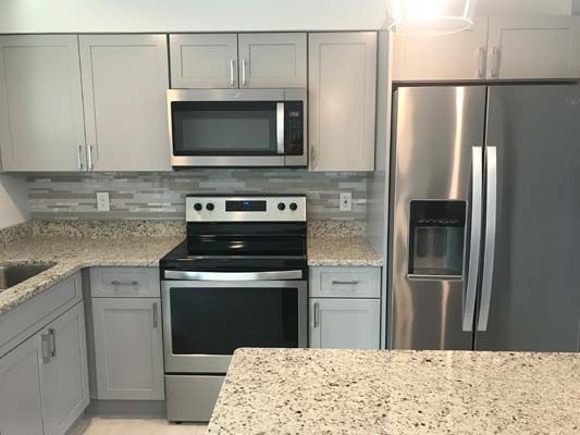 A kitchen with a stove , refrigerator , microwave and sink.