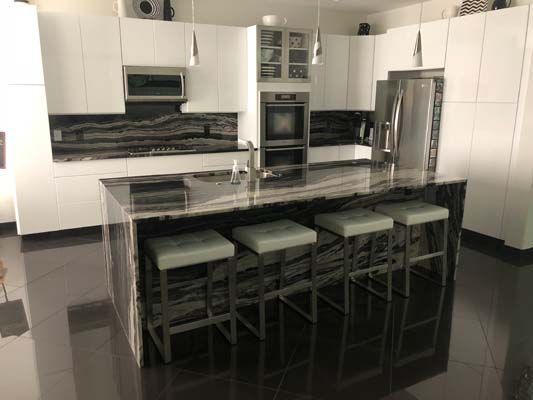A kitchen with a large island and stools in it.