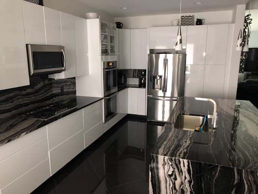 A kitchen with black counter tops and white cabinets