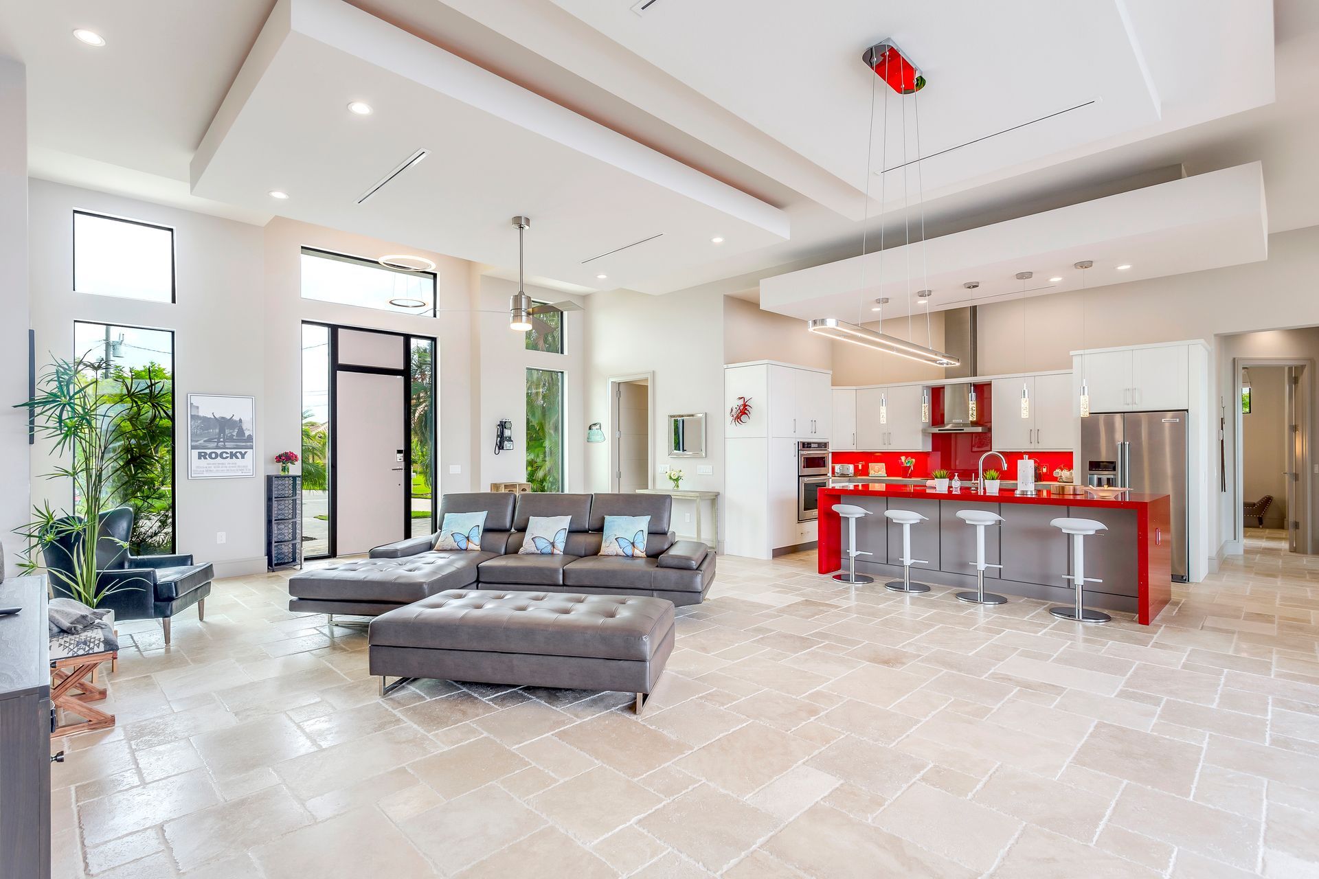 A living room with a couch and ottoman and a kitchen