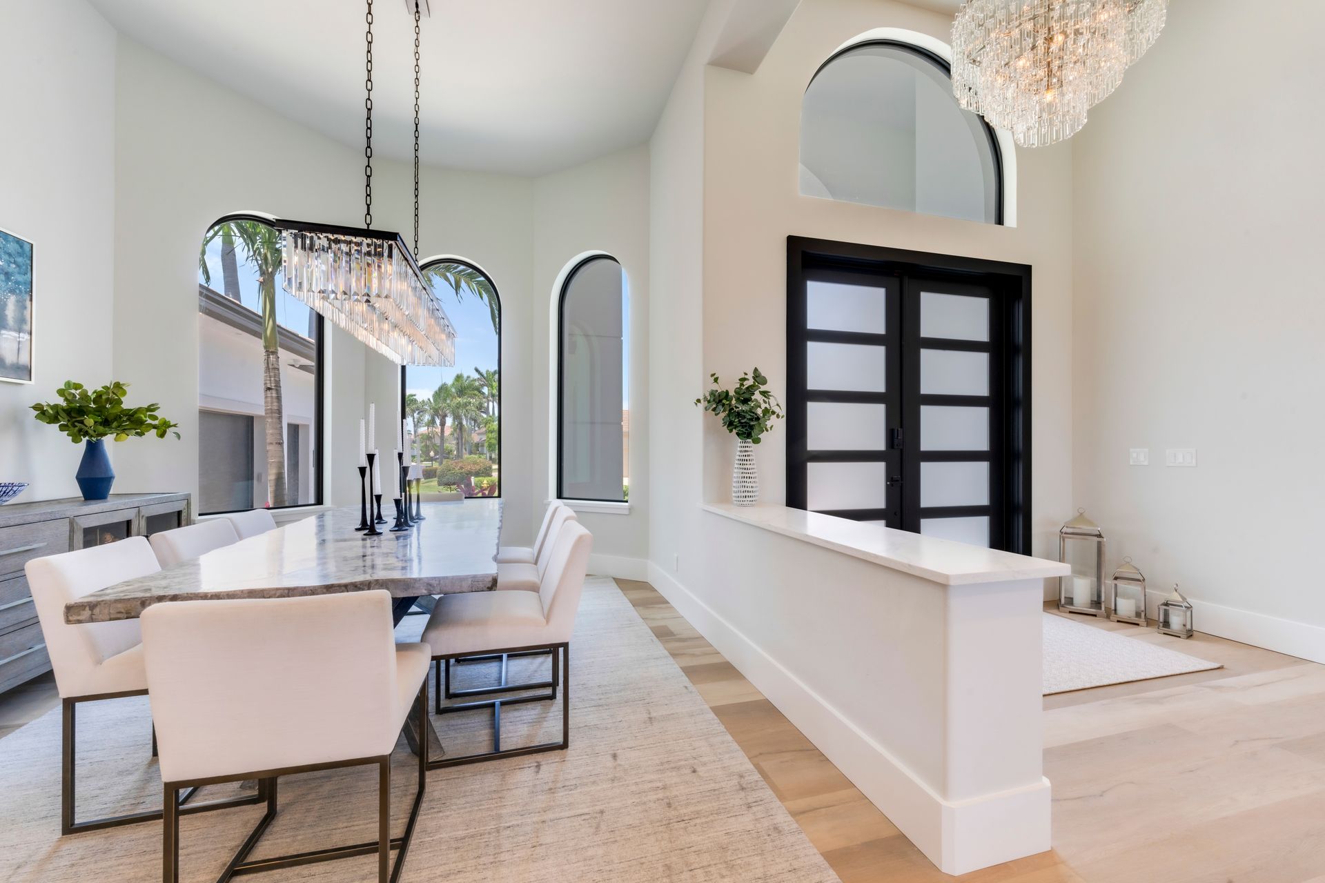 A dining room with a table and chairs and a chandelier hanging from the ceiling.