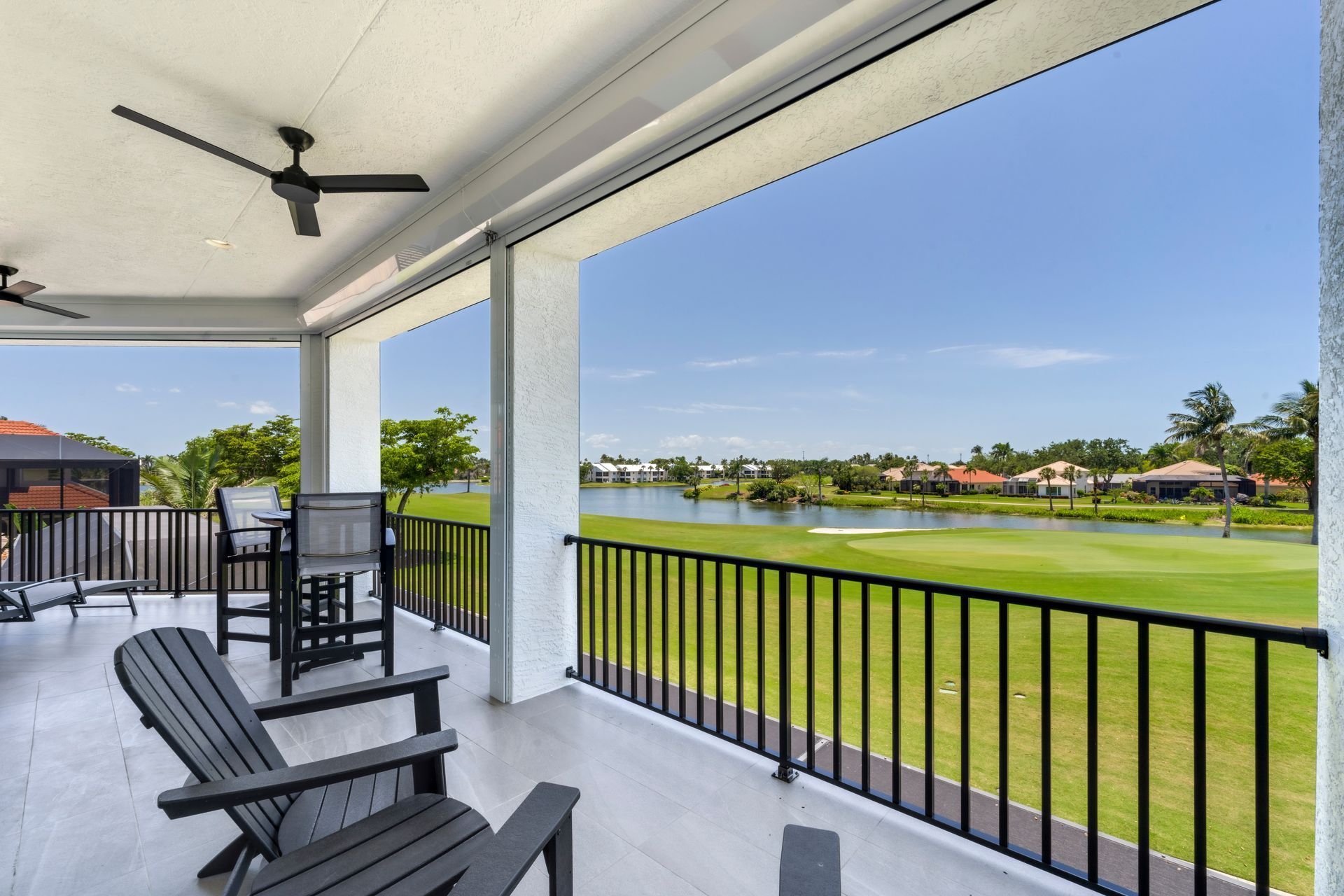 A balcony with chairs and a ceiling fan overlooking a golf course