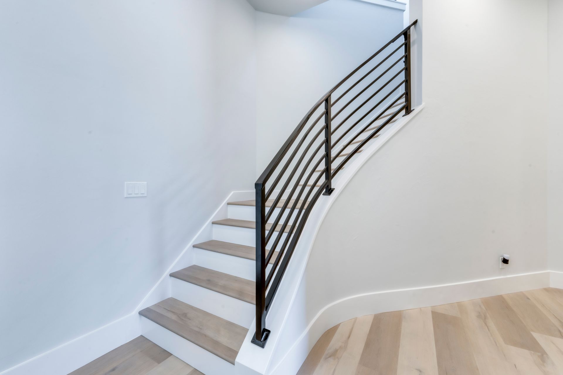 A staircase with a metal railing and wooden steps in an empty room.