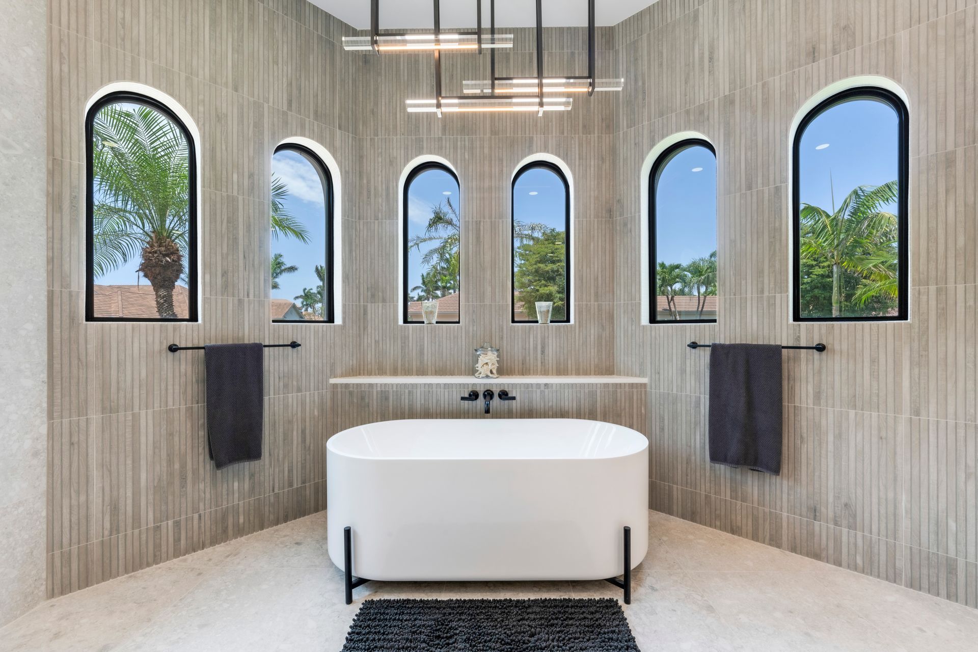 A bathroom with a tub , sink , mirror and window.