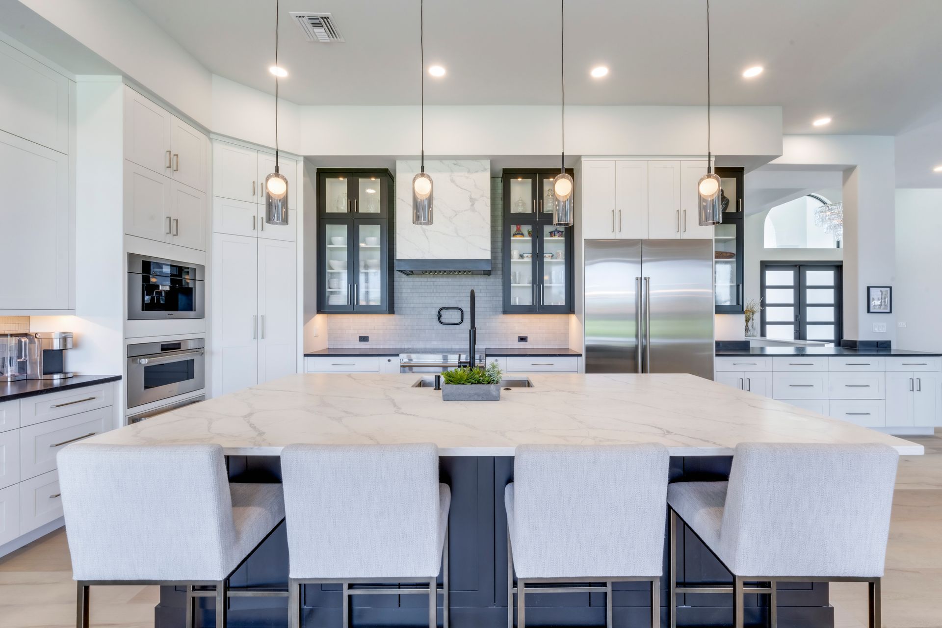 A kitchen with white cabinets and stainless steel appliances and a large island.