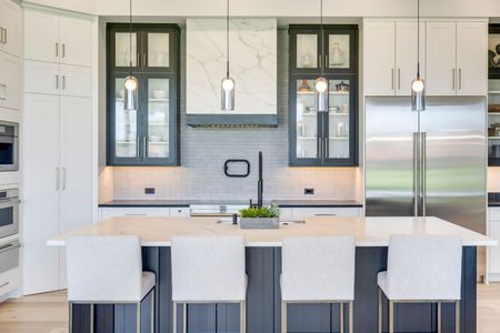 A kitchen with white cabinets , stainless steel appliances , and a large island.