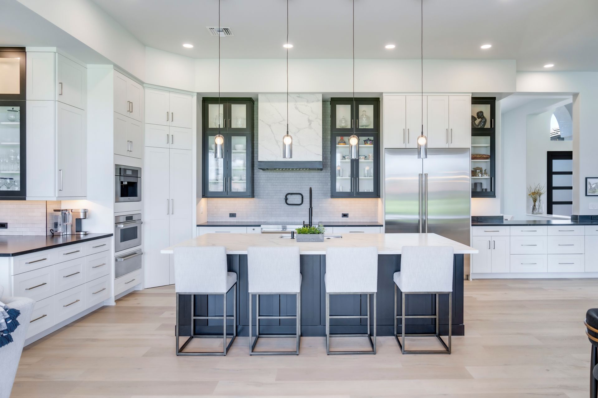 A kitchen with white cabinets and stainless steel appliances and a large island.