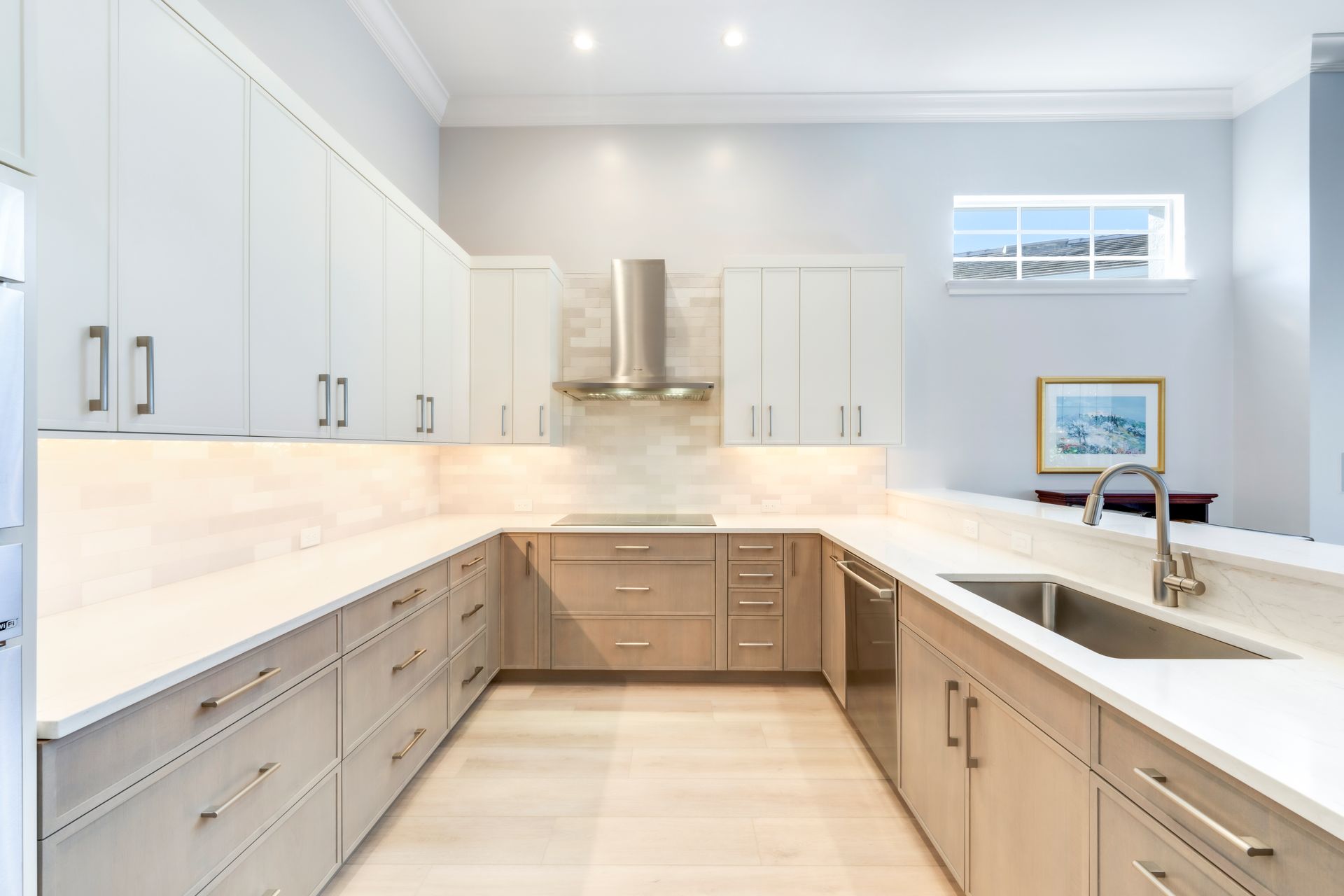 A kitchen with white cabinets , stainless steel appliances , a sink and a stove.