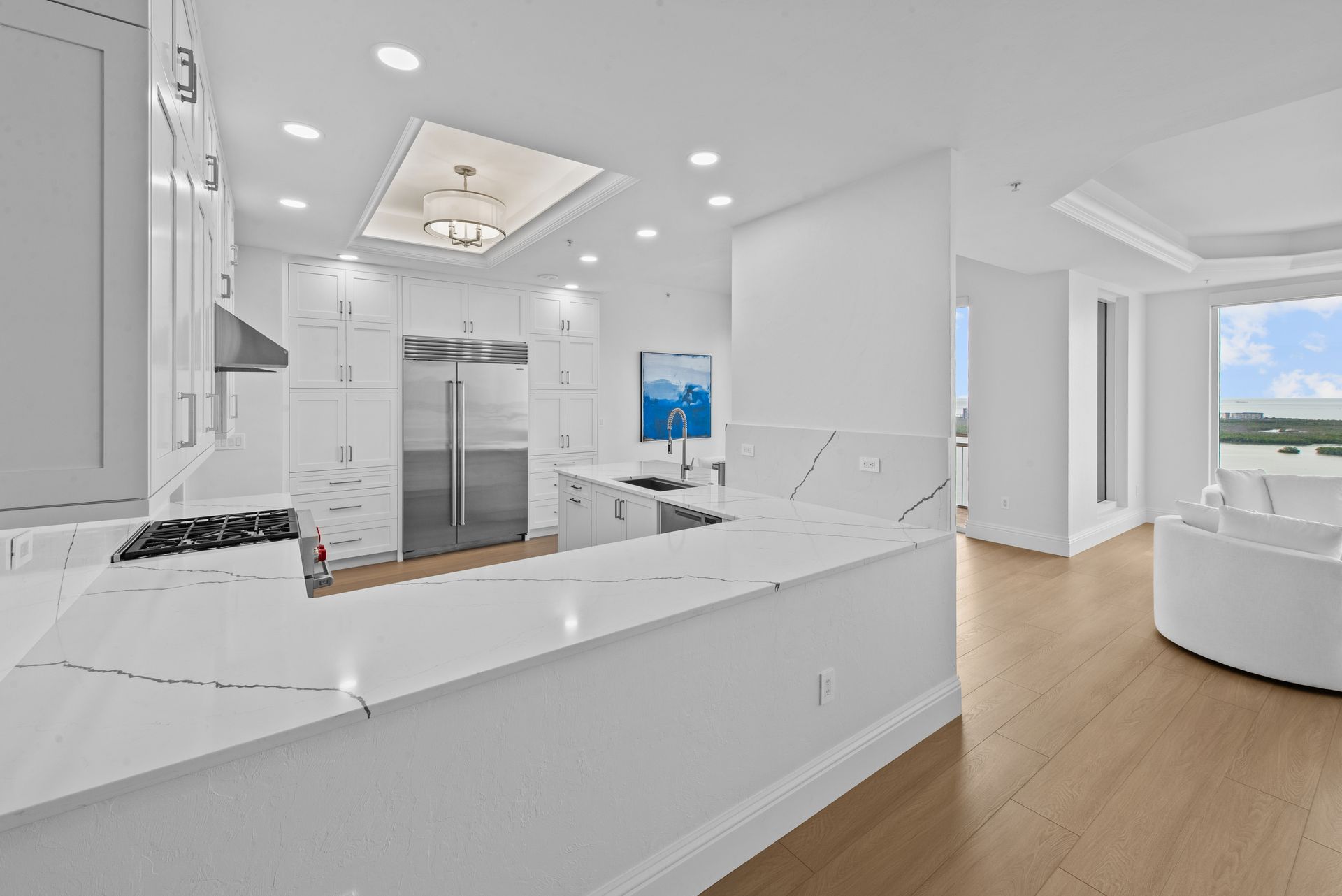 A kitchen with white cabinets , stainless steel appliances , and a large window.