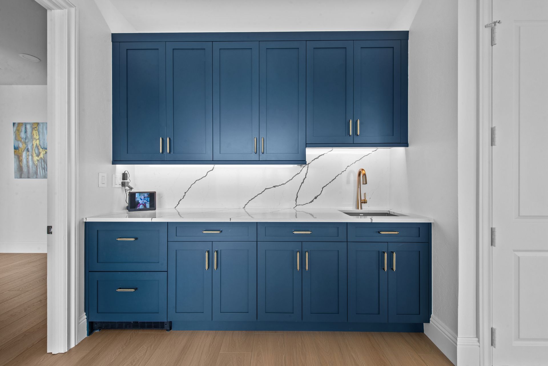 A kitchen with blue cabinets and white counter tops.
