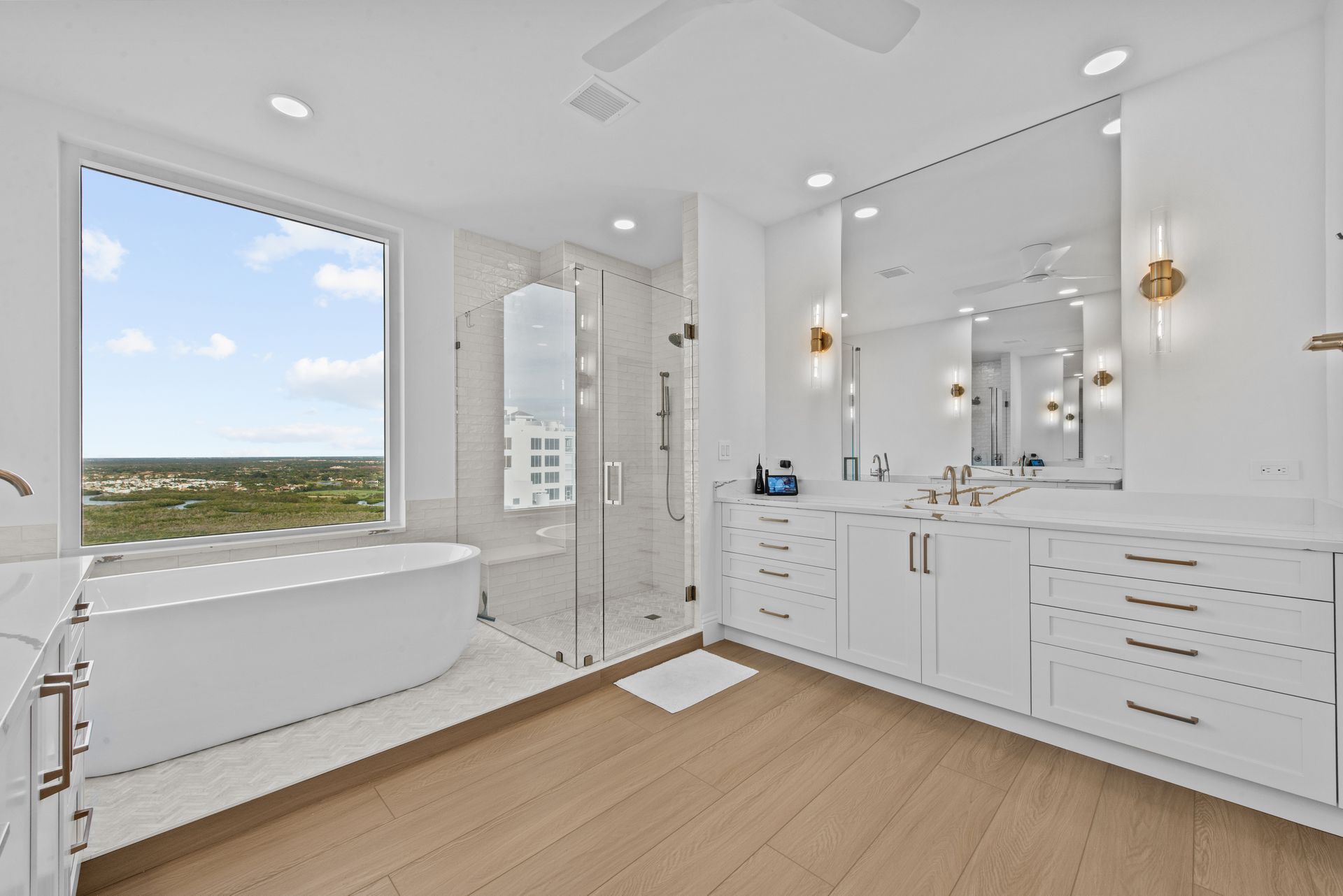 A bathroom with a tub , sink , mirror and window