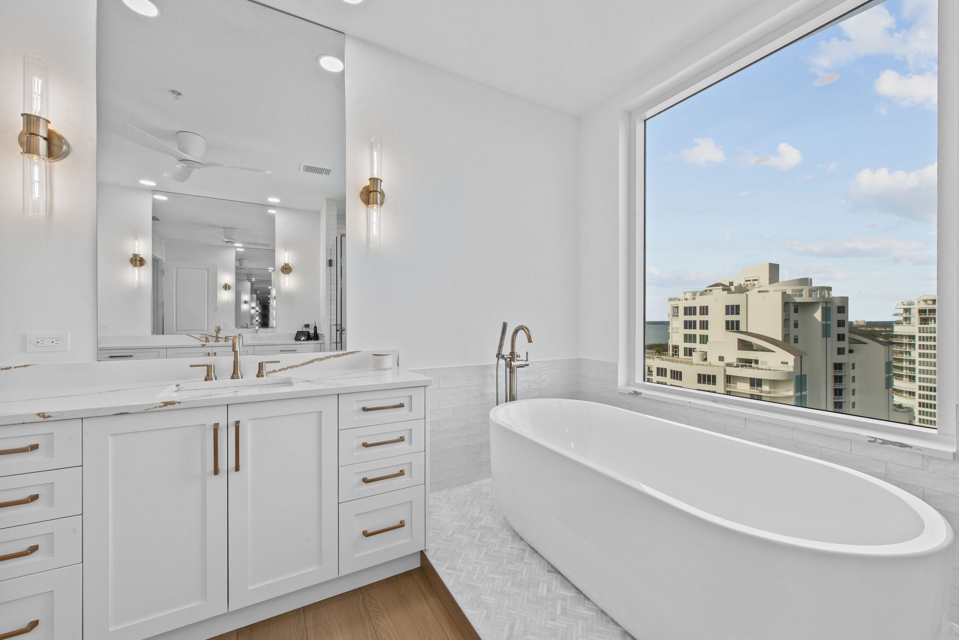 A bathroom with a tub , sink , mirror and window.