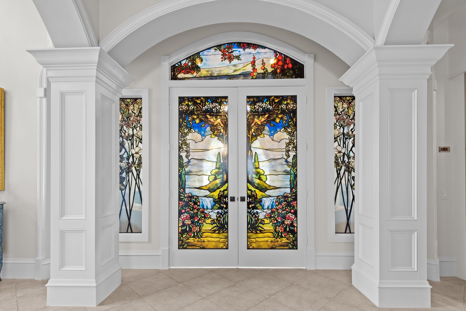 A hallway with a stained glass door and columns.