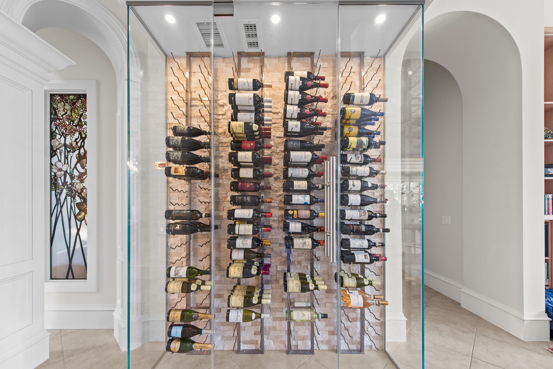 A wine cellar filled with lots of bottles of wine behind a glass wall.