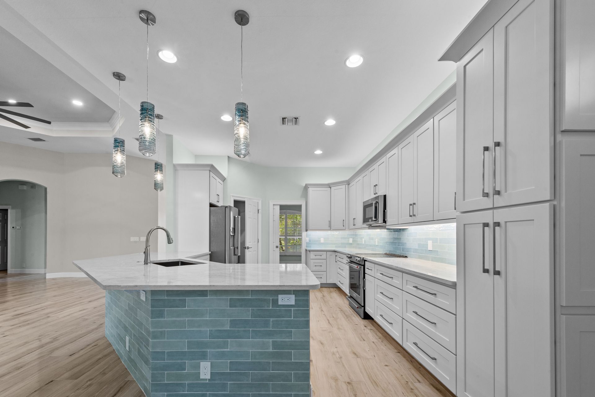 A kitchen with white cabinets and a large island in the middle.