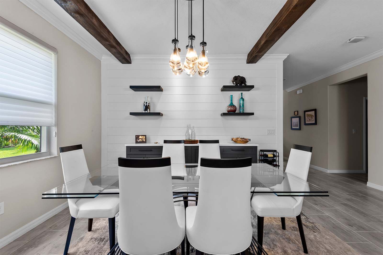 A dining room with a glass table and white chairs