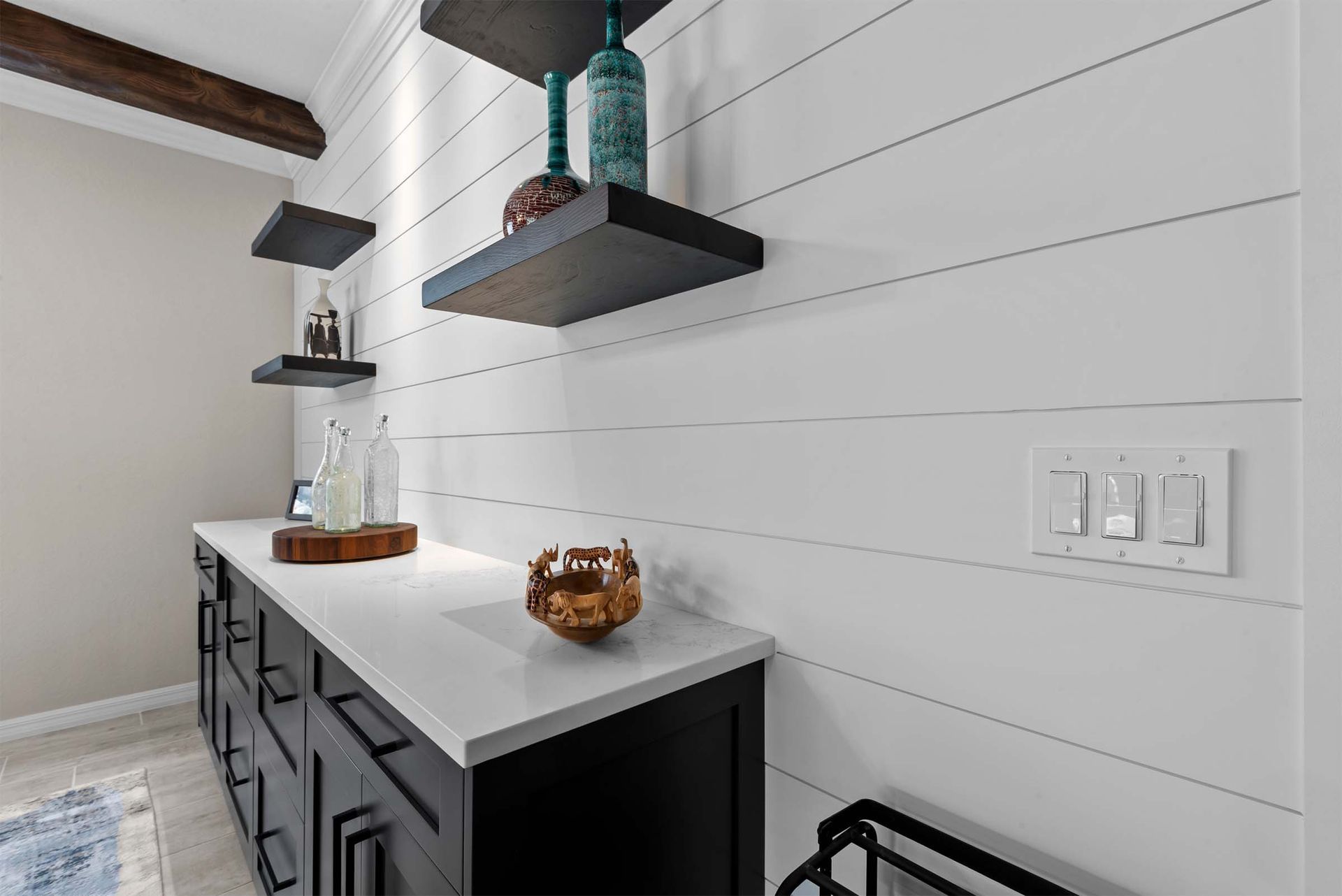 A kitchen with a long counter and shelves on the wall.