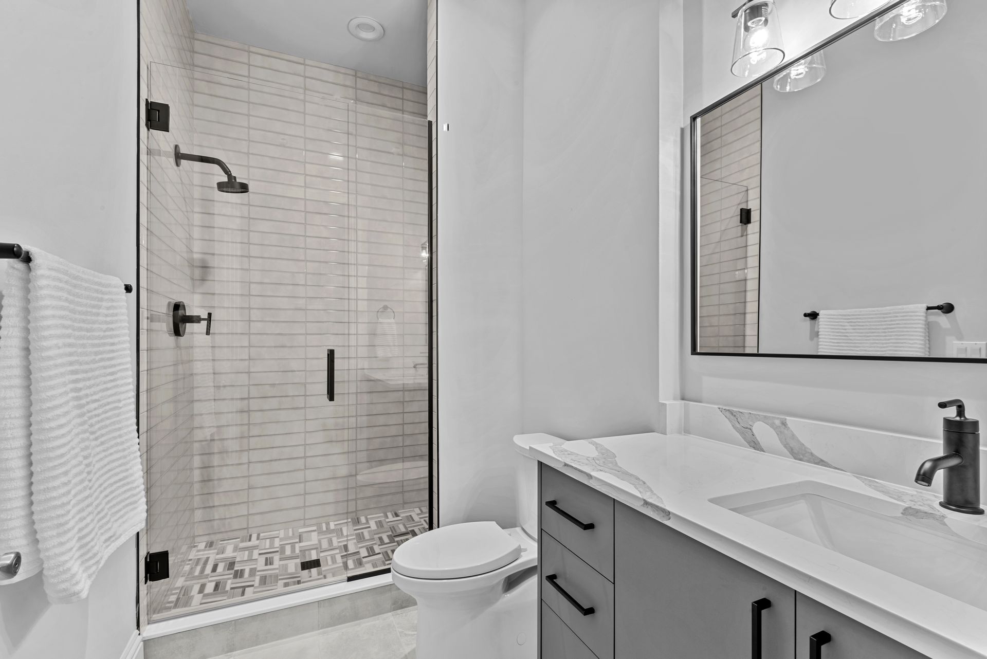 A bathroom with a toilet , sink , shower and mirror.