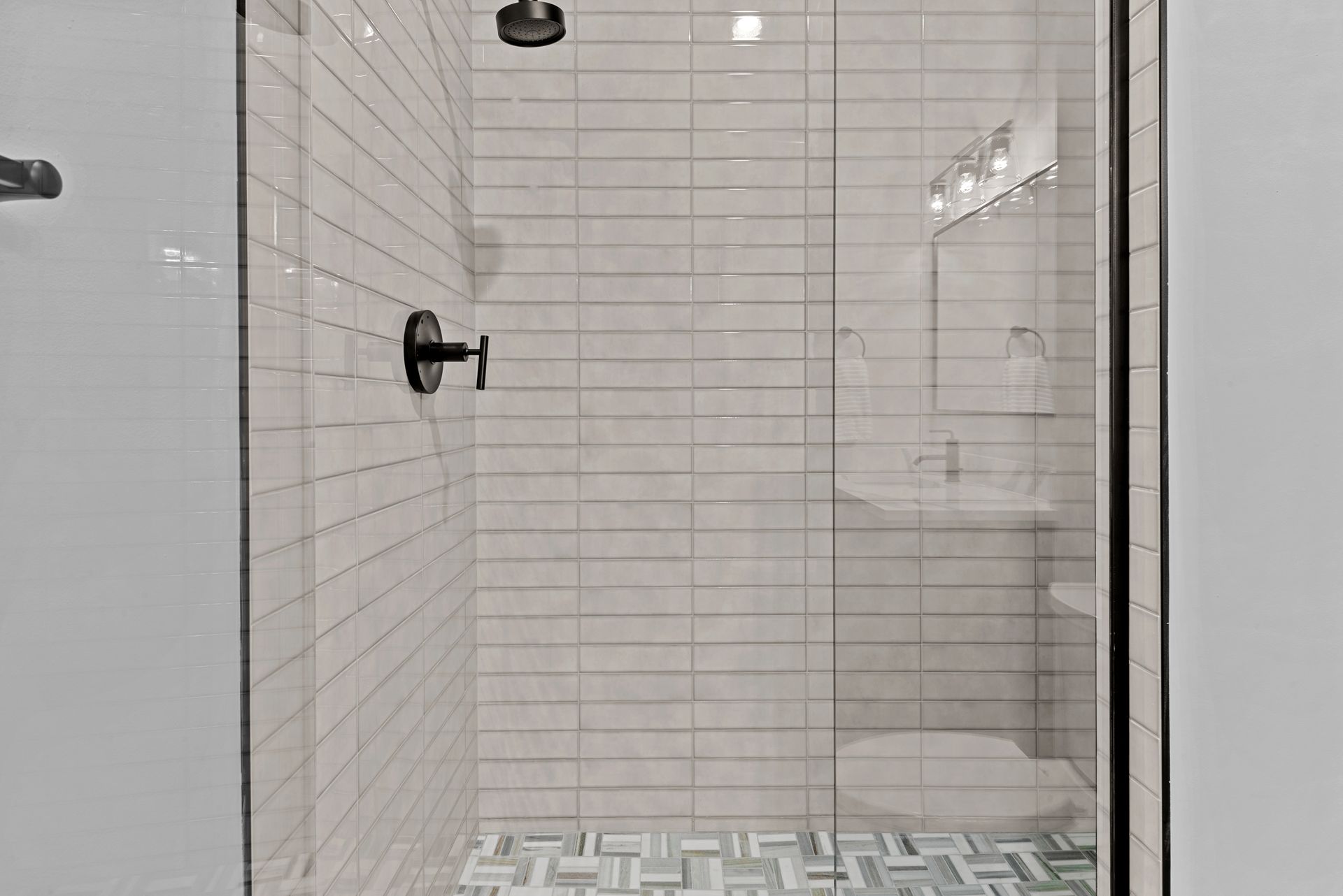 A bathroom with a walk in shower , toilet , sink and mirror.