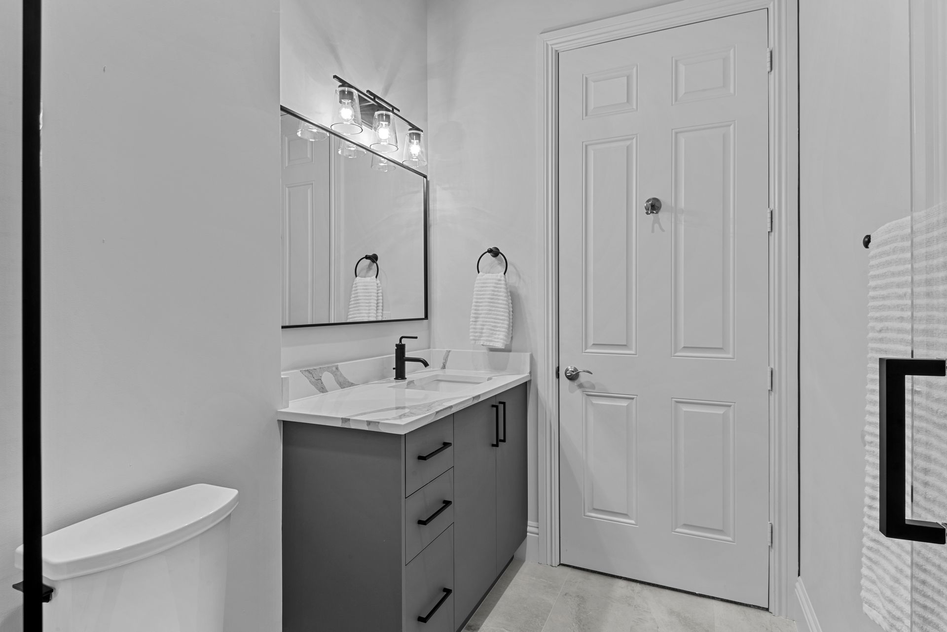 A bathroom with a toilet , sink , mirror and door.