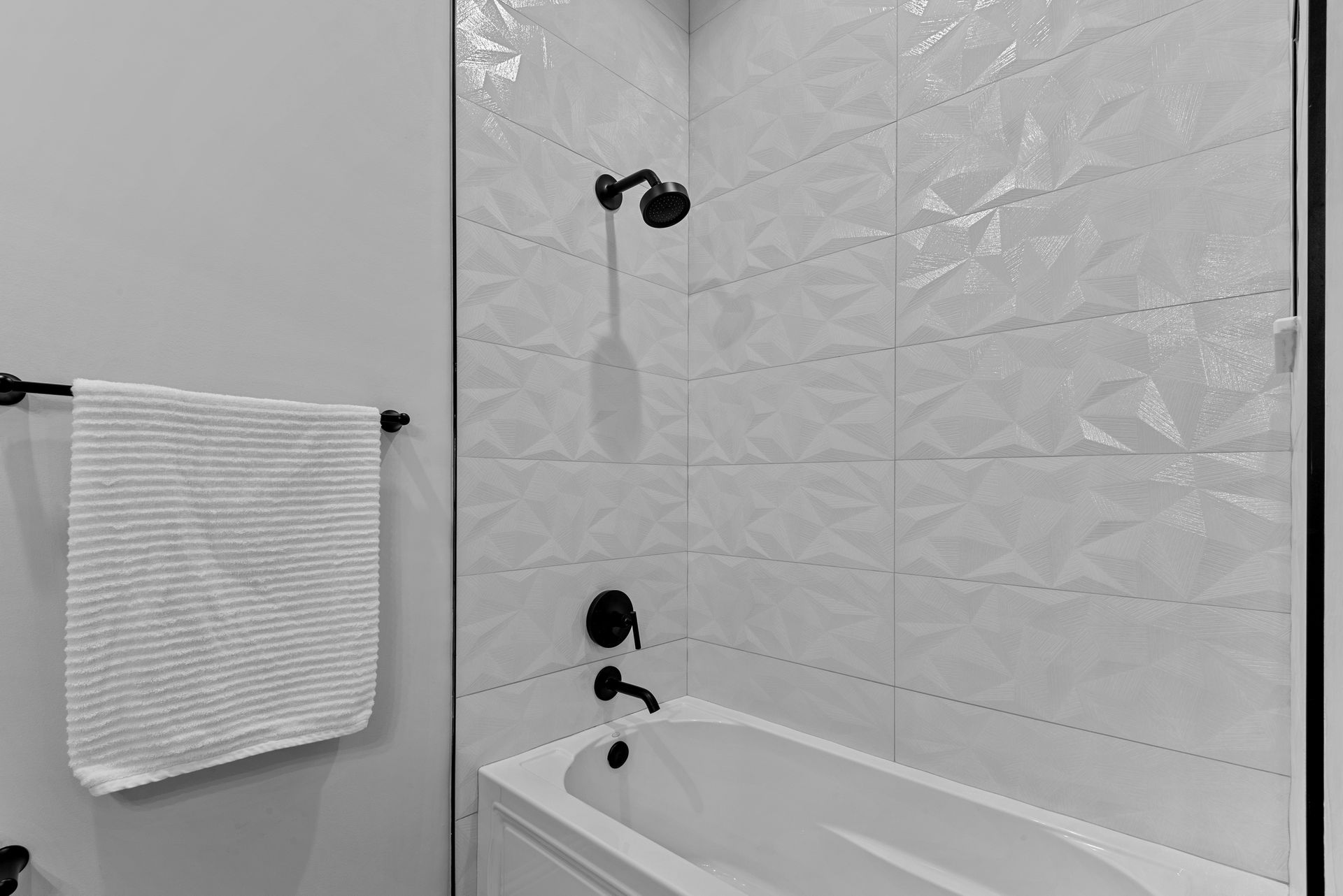 A bathroom with a bathtub , shower , and towel rack.