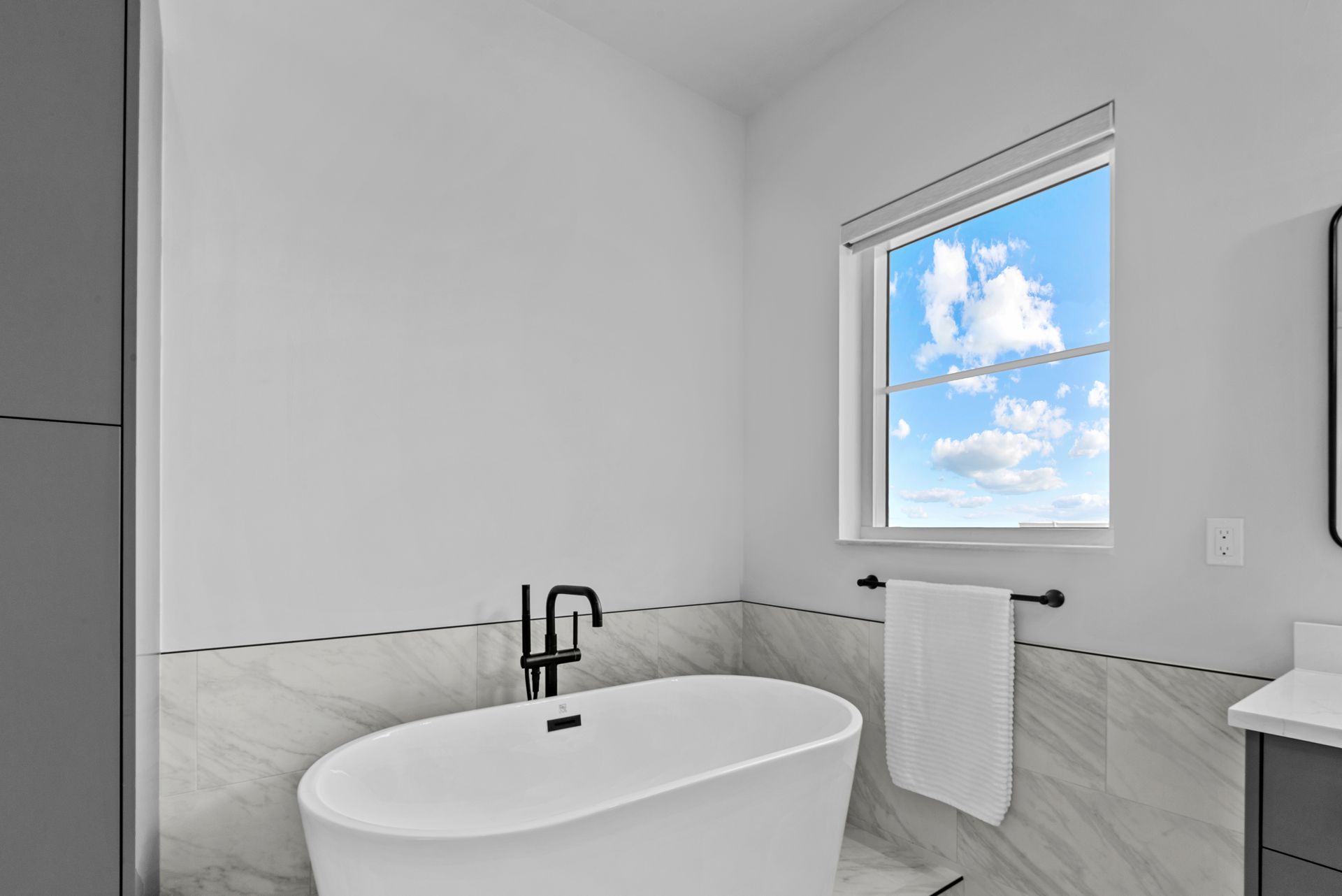 A bathroom with a tub , sink , mirror and window.