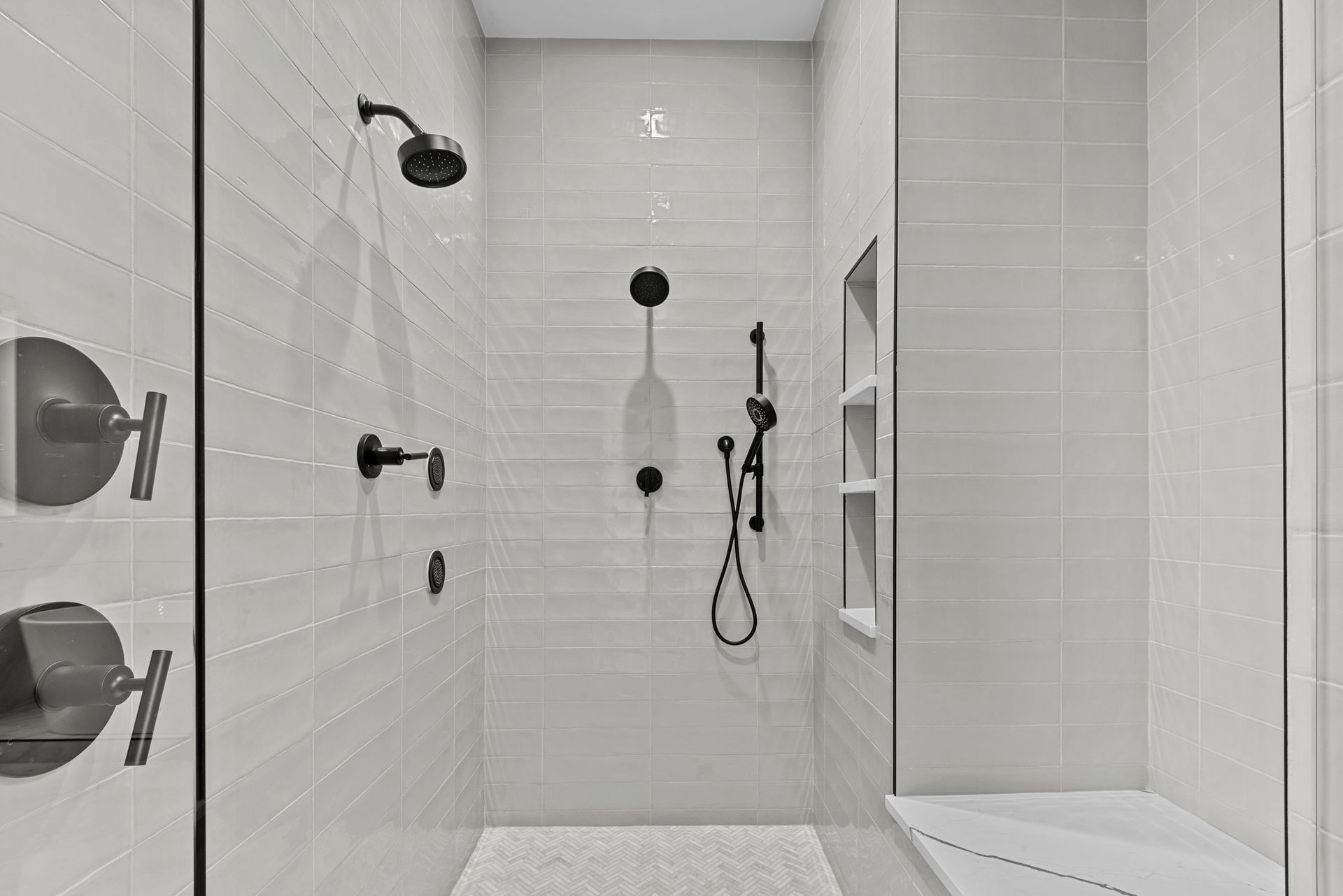 A black and white photo of a bathroom with a walk in shower.