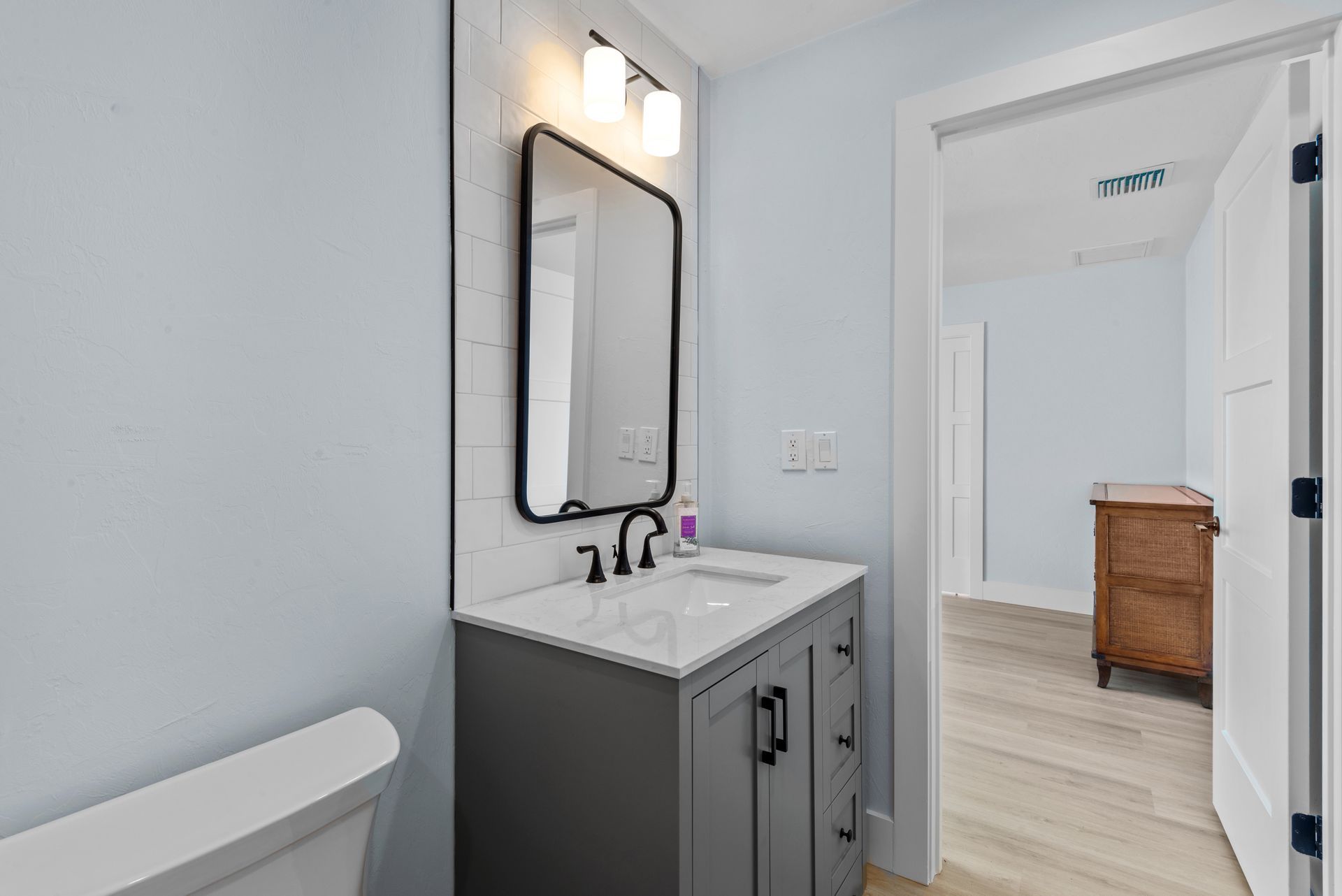 A bathroom with a sink , mirror and toilet.