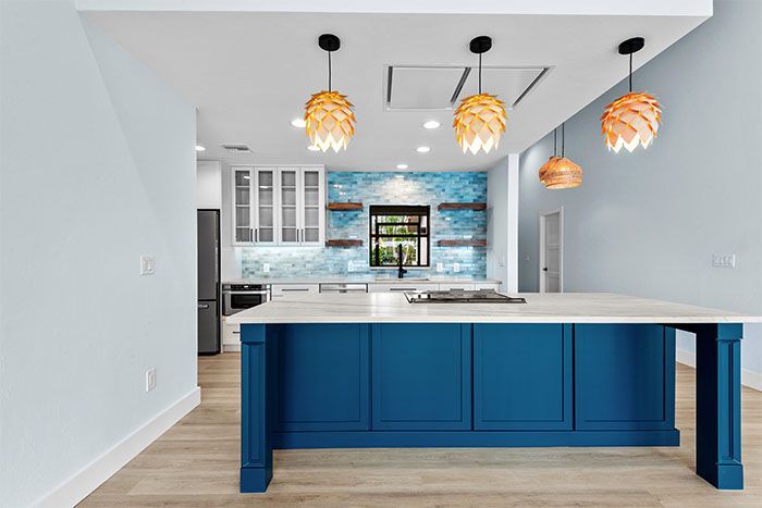 A kitchen with blue cabinets and a large island in the middle.