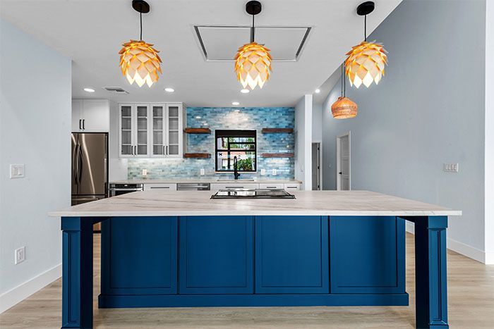 A kitchen with blue cabinets and a large island in the middle.