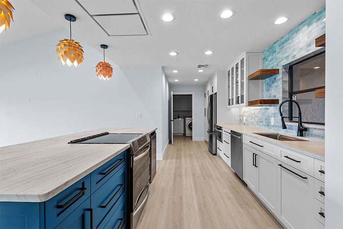 A kitchen with blue cabinets , white cabinets , stainless steel appliances and hardwood floors.