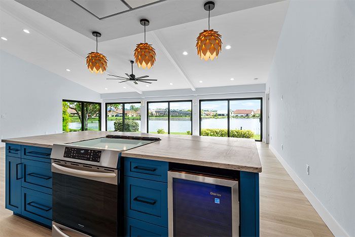 A kitchen with blue cabinets , stainless steel appliances , a refrigerator and a large island.