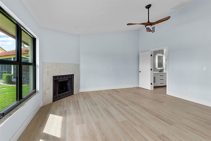 An empty living room with a fireplace and a ceiling fan.