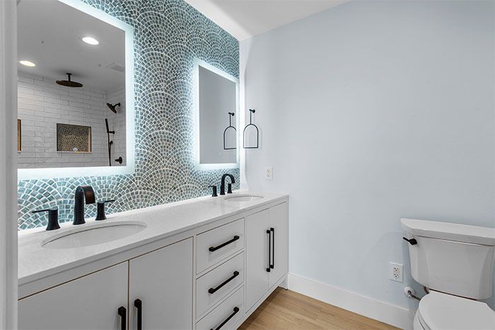A bathroom with two sinks , a toilet and a mirror.