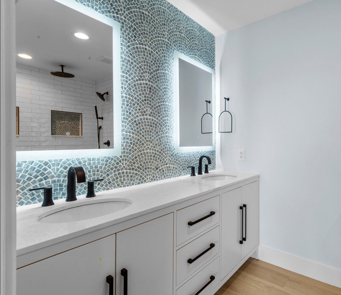 A bathroom with two sinks , a mirror and a shower.