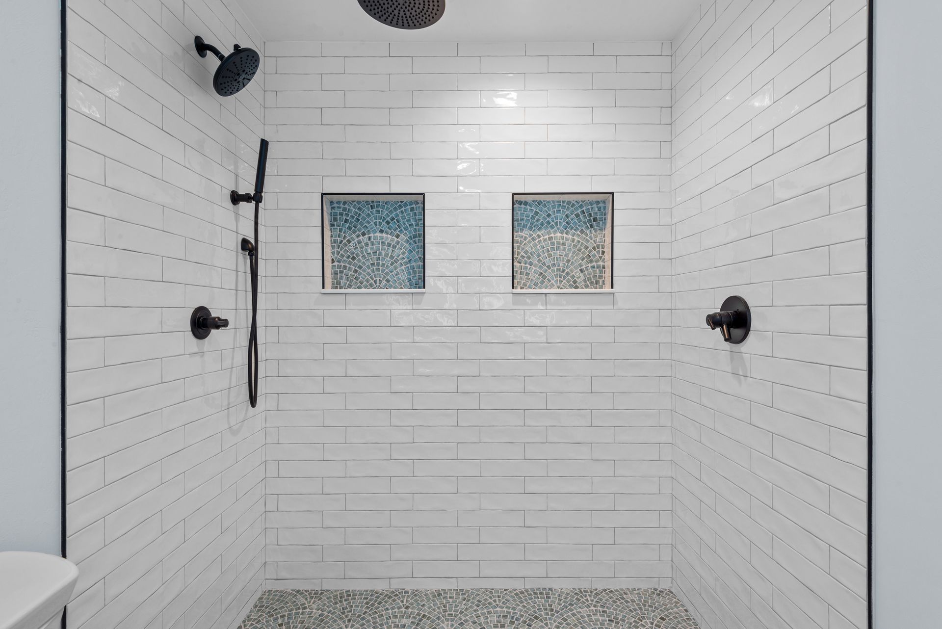 A bathroom with a walk in shower and two shower heads.