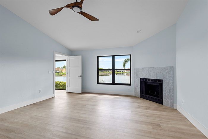 An empty living room with a fireplace and ceiling fan.