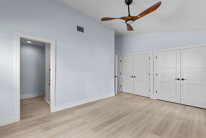 An empty room with a ceiling fan and wooden floors.