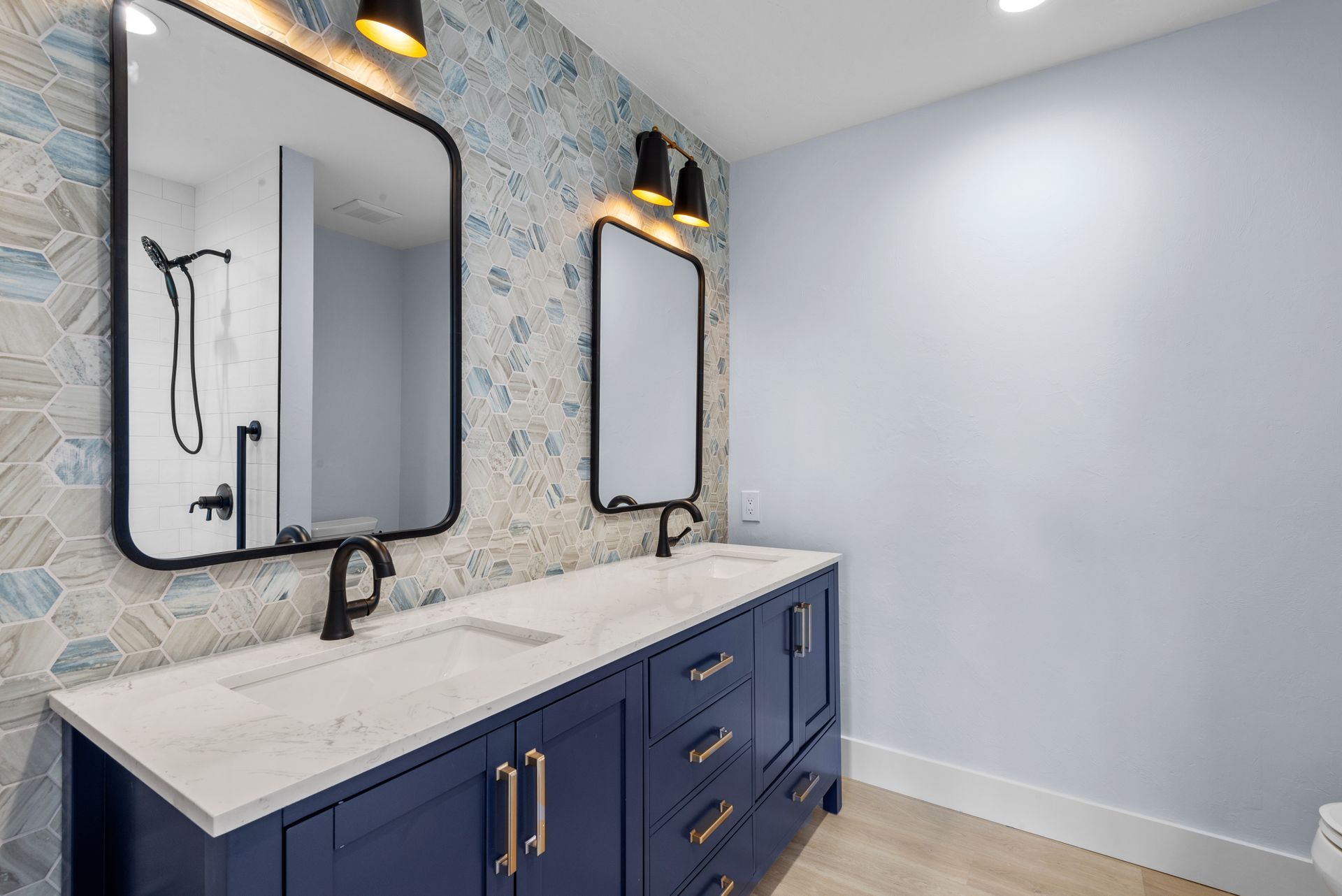 A bathroom with two sinks , two mirrors and a toilet.